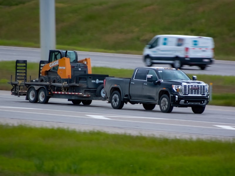 Chevrolet Sierra towing heavy equipment on the highway